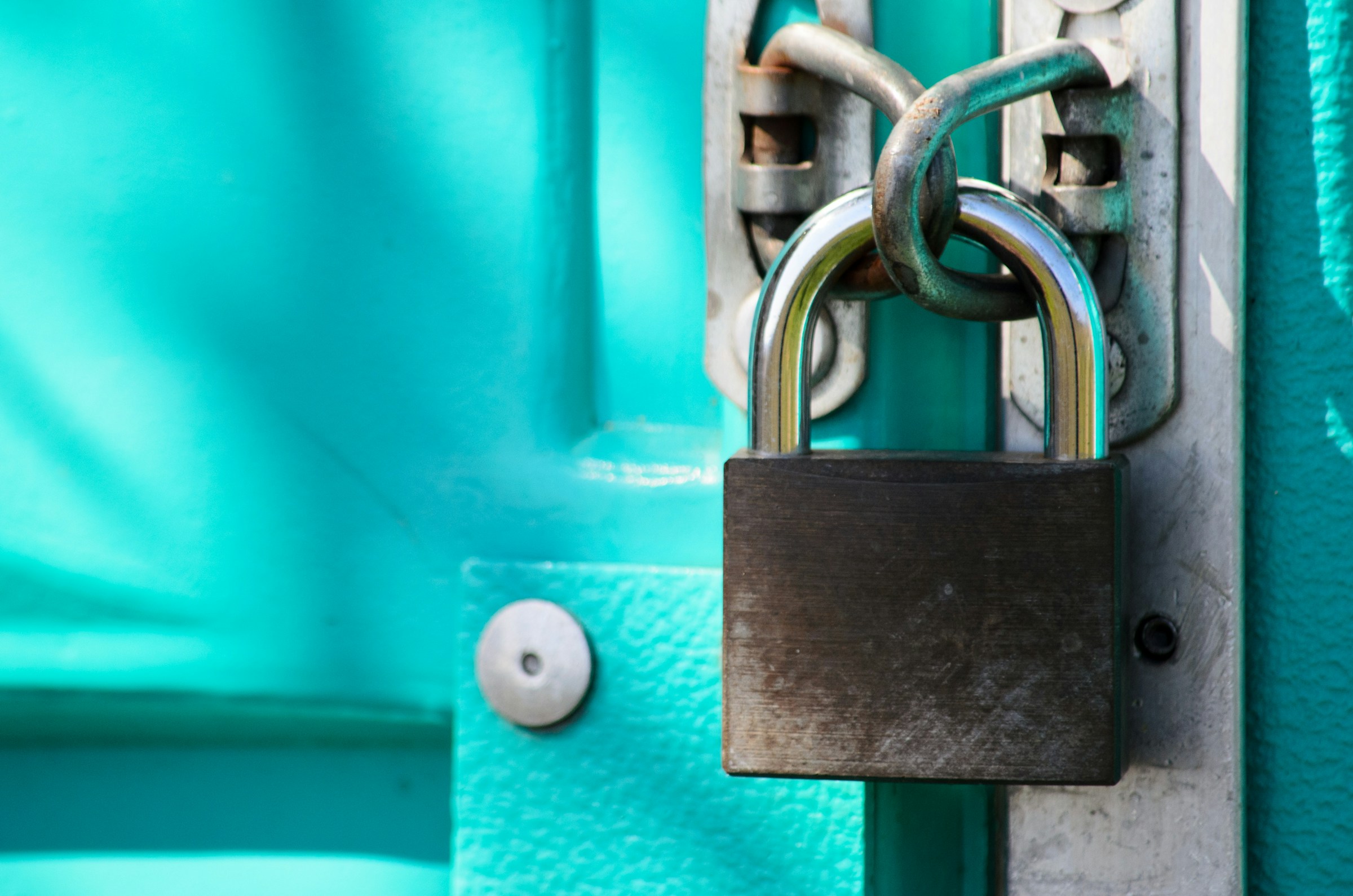 Padlock securing a bright turquoise door