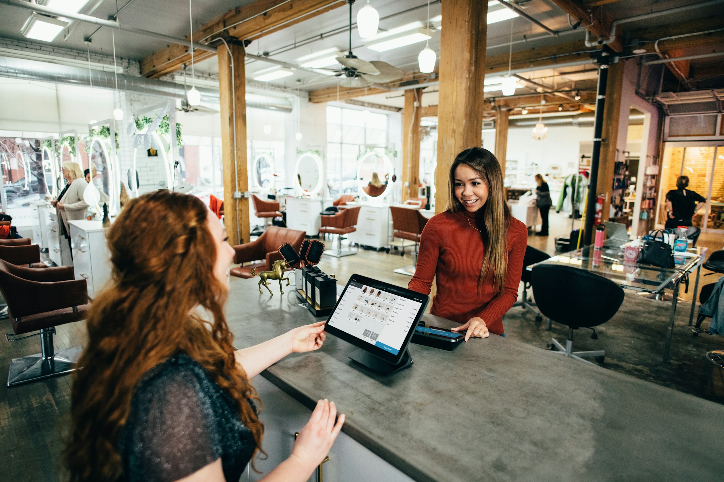 Staff greeting a customer in a bright, modern salon